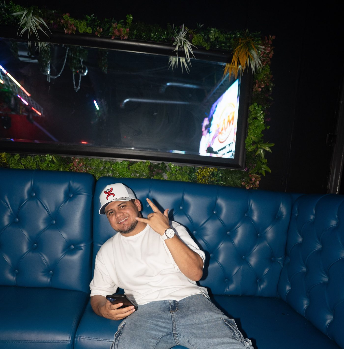 A guest relaxing in a blue tufted VIP booth